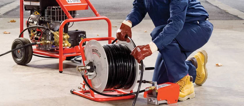 Técnico da Desentupidora Pinheiro operando máquina desentupidora com cabo de aço